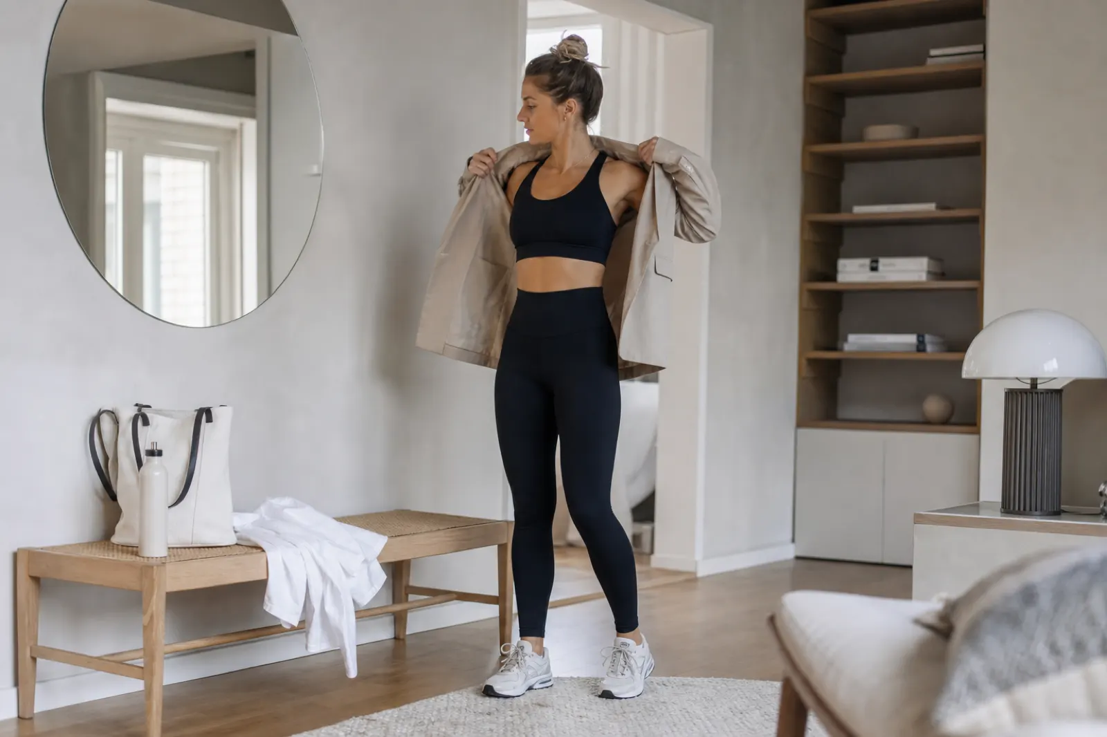 Person i mörka tights och sporttopp som lägger till en ljus kavaj för en athleisure-outfit