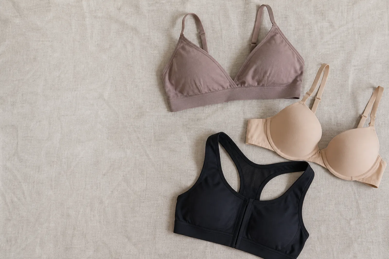 Bralette, t-shirt-bh och sport-bh jämförda på ett ljust tygunderlag