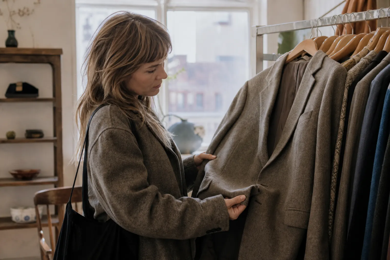 Person som granskar material och sömmar på en secondhandkavaj i en liten butik