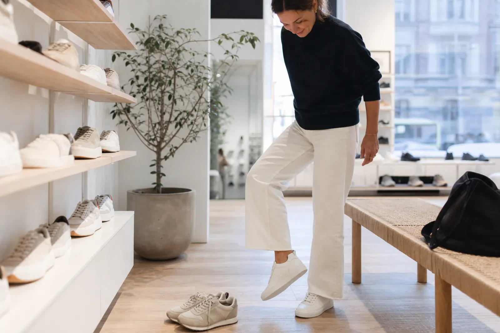 Person som provar vita sneakers och kontrollerar passformen i en ljus skobutik